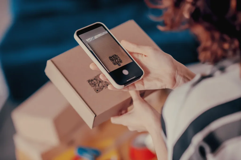 Person using smartphone to scan QR code on a smart package, accessing digital content